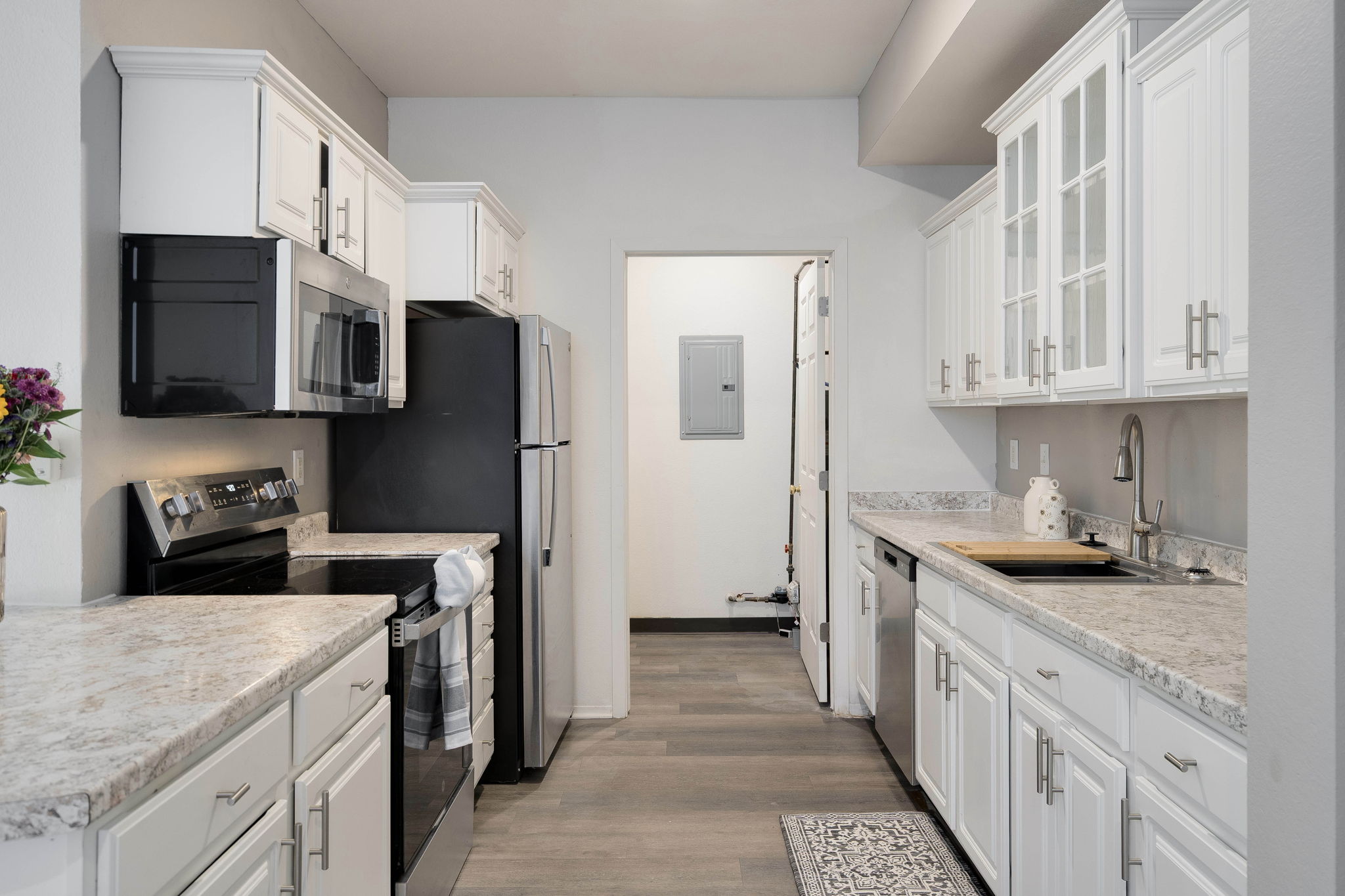 A kitchen with white cabinets and black appliances.